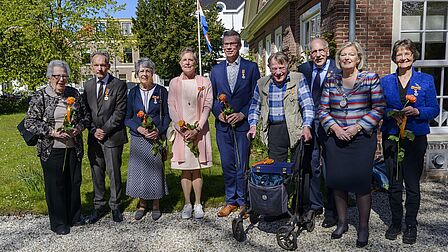 Groepsfoto van 8 gedecoreerden en burgemeester voor de Dorpskerk in Bloemendaal